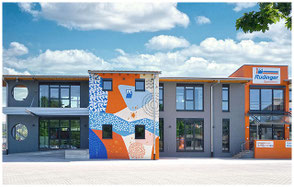 Der jüngste Neubau am Hauptsitz der Spedition: das Jagstforum. Es besteht aus etwa drei gleichbreiten Segmenten. Das mittlere ist ein Kunstwerk mit den Hauptfarben Orange und Blau.