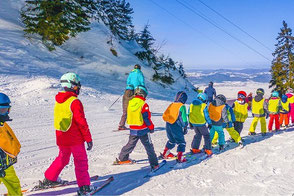 Kinder in einer Reihe beim Skikurs.