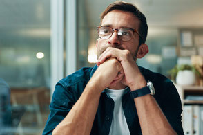 Ein Mann mit Brille sitzt nachdenklich am Schreibtisch