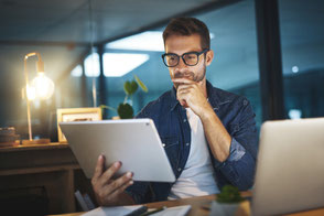 Ein Finanzberater schaut in seinem Büro auf ein Tablet