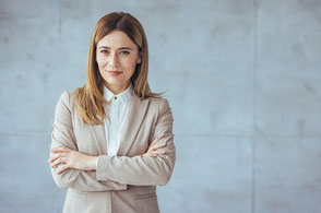 Eine junge Business-Dame steht vor einer Scihbetonwand