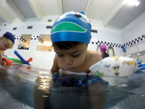Junge pustet im Schwimmkurs ins Wasser