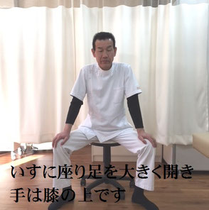 いすに座り足を大きく開き、手はひざの上です。