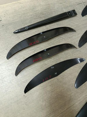 les 3 stabs et le fuselage arrière du foil aeromod V3 démontés, en carbone apparent, déco sans les bandes de peintre, sérigraphies des lettres rouge cerise