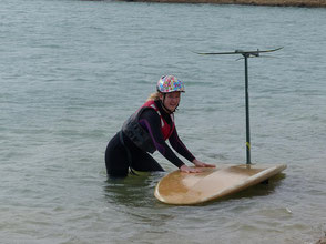 Célia Maréchal,  en combinaison et casque, dans l'eau avec une planche à voile et un windfoil Aeromod