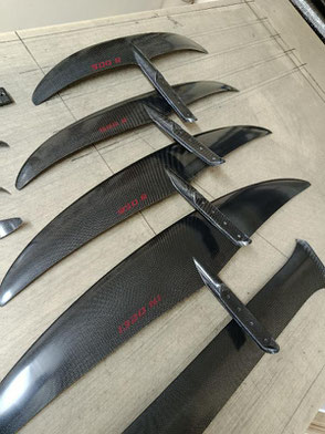 les 4 ailes du foil aeromod V3 démontées, et le mat, en carbone apparent, déco sans les bandes de peintre, sérigraphies des lettres rouge cerise