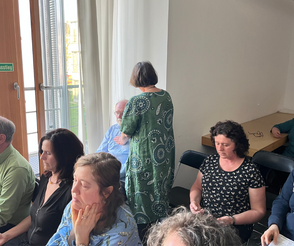 Ina Paulus legt einem Teilnehmer der Heilsession eine Hnad auf den Bach und eine auf den Rücken
