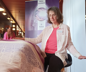 Geistheilerin Ina Paulus legt einer Klientin eine Hand auf und hält eine Hand neben sich um Energien in die Erde abzuleiten