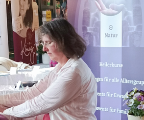 Ina Paulus legt einer Klientin die Hände an ihrem Messestand im Rahmen einer Einzelsitzung auf