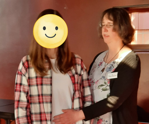 Ina Paulus legt einer Teilnehmerin während einer Heilsession bei den Naturheiltagen eine Hnad auf den Bauch und die ander auf den Rücken.