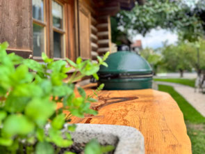 Massive Baumstammbohle aus Geisinger Esche mit Kräutern und integriertem Big Green Egg als Teil einer Outdoor-Küche nach Maß