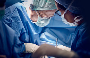 Chirurgen in OP-Kleidung und Mundschutz während einer Operation im Operationssaal.