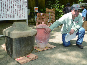 厨子に掘られてある文字を解説する比嘉館長。手前は砂岩製の岳母の石厨子。奥は実母の厨子甕=5日、サビチ洞事務所前