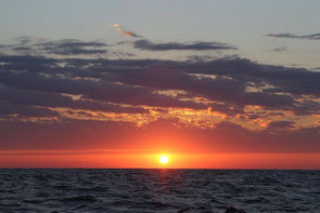 Freies Foto von Pixabay. Sonnenuntergang über dem dunkel daliegenden Atlantik; leicht mit Wolken verhangener Himmel in orangerot, dunkelviolett, blau.