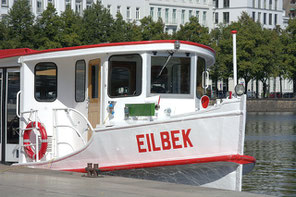 Das weiß gestrichene Alsterboot mit roten Akzenten wartet an der Anlegestelle