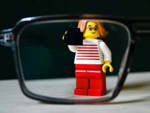 Lego-Männchen schaut durch großes Brillenglas
