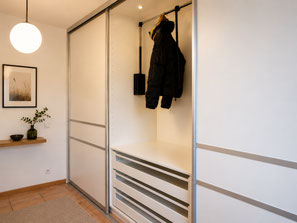 Maßgefertigte Gleitschiebetüren für ein Garderobenzimmer in Geisingen mit raumhohem Garderobenschrank, Kleiderlift, Schubladen und individuell geplantem Stauraum.