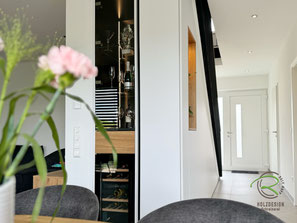 Einbaumöbel unter Treppe mit Glasvitrine mit Schwarzem Korpus und senkrechter LED Beleuchtung, Schublade in Eiche furniert u. schmalem Weinkühlschrank, Treppenschrank als Garderobeschrank mit Dekorationsnische u. Schuhschrank