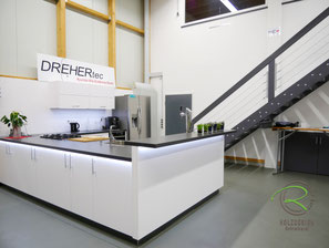 Moderne Küche mit Theke und Kochinsel nach Maß. Weiße Schreinerküche mit dunkler Arbeitsplatte, integrierter Spüle, RGB-Beleuchtung und großzügiger Arbeitsfläche für Kochen und Kommunikation.