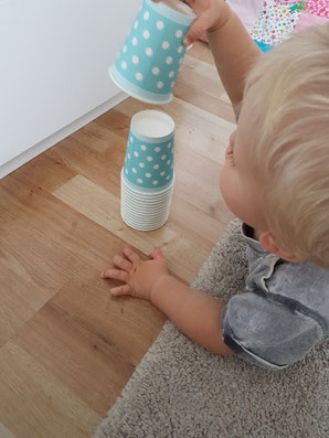 Kleinkind baut einen Turm aus Pappbechern