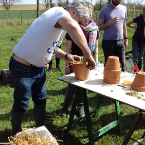 photo montrant la fabrication des nids à insectes avec des pots en terre cuite, de la paille et du grillage