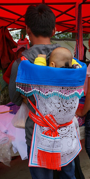 Babytrage mit lokaler Batik; Kind traditionell "geschoren"