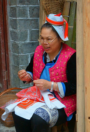 Frau mit typischer Kopfbedeckung beim Sticken 