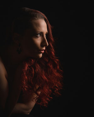 Stimmungsvolles Frauenportrait im Seitenlicht, ruhiger Ausdruck vor dunklem Hintergrund