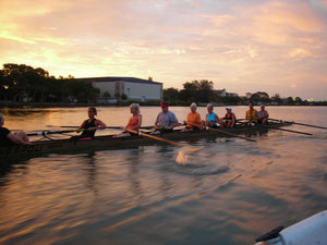 An eight rowing as the sun comes up on smooth water