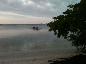 An eight leaving the boatyard on mirror flat water