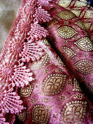 Close up of embroidered pewter design & pink lace border on grape-coloured section of silk brocade Indian throw