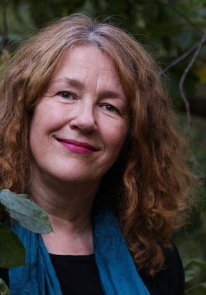 Trauerrednerin Margit Vida lächelt in einem Garten