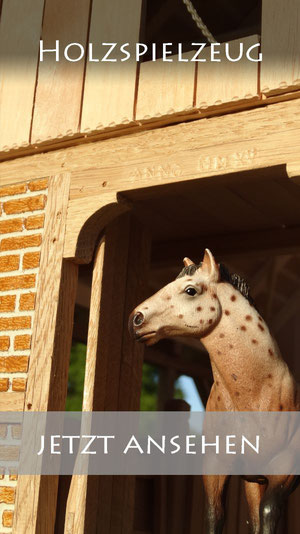 Holzstall von 3zinken.de mit einem Schleich Pferd im Tor des großen Pferdestalls.