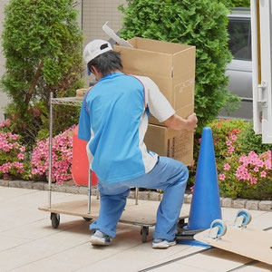 重い荷物を持ち腰に負担をかける男性