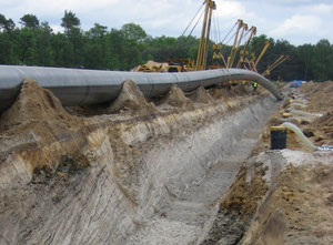 Abb. 2. Verlegung des Rohres in den Leitungsgraben bei Fürstenwalde. Aufgeschlossen sind im Vordergrund humose gut geschichtete Flusssande der Spree. Im Hintergrund werden sie von grauen Urstromtalsanden/-kiesen unterlagert. Foto: O. Juschus