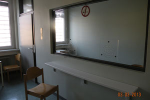 Häftling und Besucher sind durch eine Glaswand getrennt