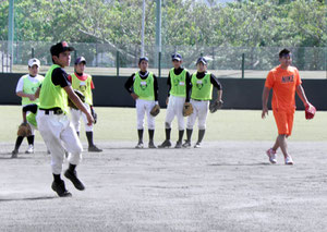 黒木さん(右側)から、守備の指導を受ける中学生=市中央運動公園野球場