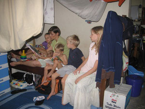 Cindy is reading to the kids on Caleb's bed. How many kids do you count? Can you find Naomi?