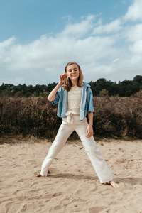vrolijk meisje poseert in de heide en legt haar haren goed-communie-lentefeest-groeifeest-spontane kinderfotografie-by Ilse Wagemakers-Fotografils-fotograaf-Kalmthout