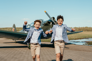 twee jongens komen vrolijk aangerend met een vliegtuigje op de achtegrond-communie-lentefeest-groeifeest-vormsel-kinderportret-by Fotografils-Ilse Wagemakers-fotograaf-Brasschaat