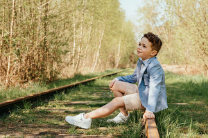 portret van jongen zittend op een oude spoorlijn-communie-lentefeest-groeifeest-vormsel-kinderportret-by Fotografils-Ilse Wagemakers-fotograaf-Brasschaat