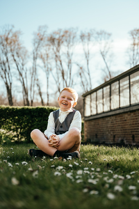 lachende jongen in grasveld met serre op de achtergrond-lentefeest-communie-groeifeest-spontane kinderfotografie-Fotografils-by Ilse Wagemakers-fotograaf-Essen