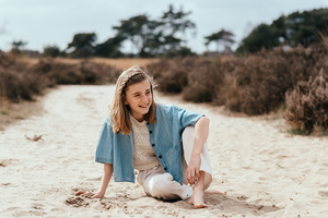 meisje poseert al zittend in het witte zand van de heide-communie-lentefeest-groeifeest-spontane kinderfotografie-by Ilse Wagemakers-Fotografils-fotograaf-Kalmthout