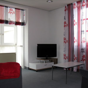 helles Wohnzimmer mit Fernseher und gemütlichen Sofas