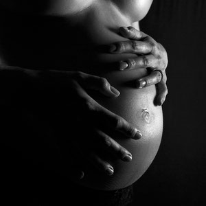 grossesse femme enceinte qui pose les mains sur son ventre en clair obscur 