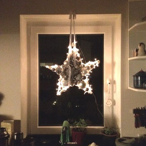 Weiß - grauer Stern mit eingearbeiteter Lichterkette im Küchenfenster.