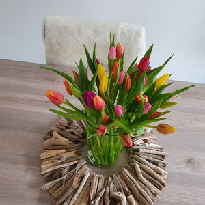 Treibholz Kranz als Tischdekoration mit einem Tulpenstrauß in der Mitte.