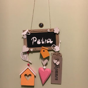 Türschild mit farbenfrohen Holzaccessoires an der Wohnungstür mit dem Namen der Bewohnerin beschriftet.