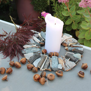 Weißer-grauer Treibholzkranz herbstlich mit Eicheln und Ahornlaub dekoriert.