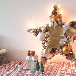 Stern mit integrierter Lichterkette in weiß - gold, mit Engeln auf Sideboard dekoriert.